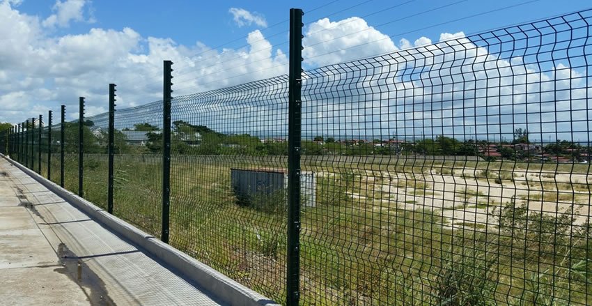 Green low security clearview fence separating roadside grassland