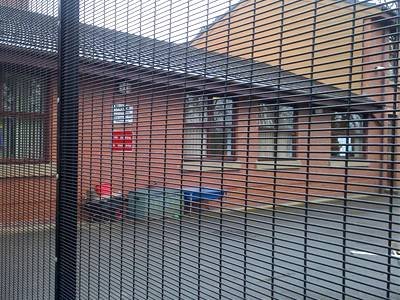 Black coated 358 welded mesh panels beside a red brick residential building