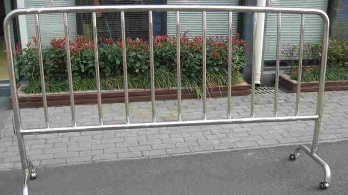 Mobile crowd control barricade with bridge feet and wheel attachments on concrete