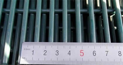 Close-up ruler measurement of approximately 12.7 mm spacing in welded 358 anti-climb mesh