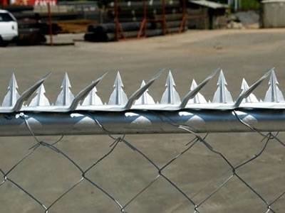 Steel security wall spikes installed above chain link fencing